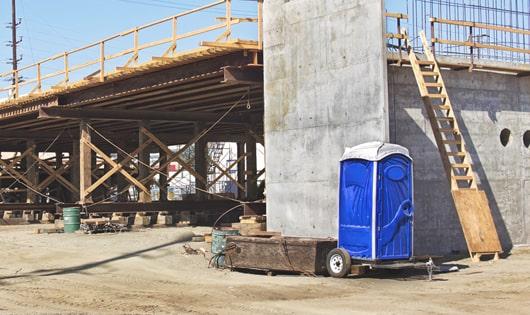 blue portable toilets arranged in a neat line on a work site